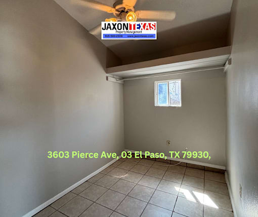 A room with a ceiling fan and a window, with a JAXON REALTY sign on the wall.