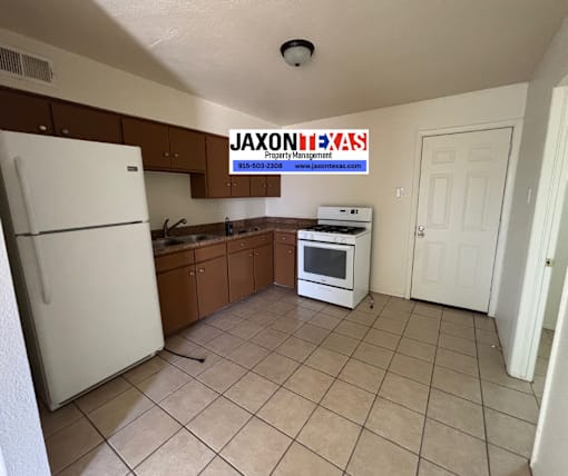 A kitchen with a refrigerator, oven, and cabinets.