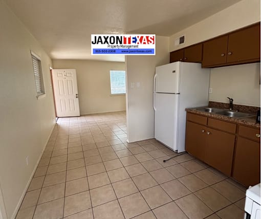 A kitchen area with a white fridge and brown cabinets.