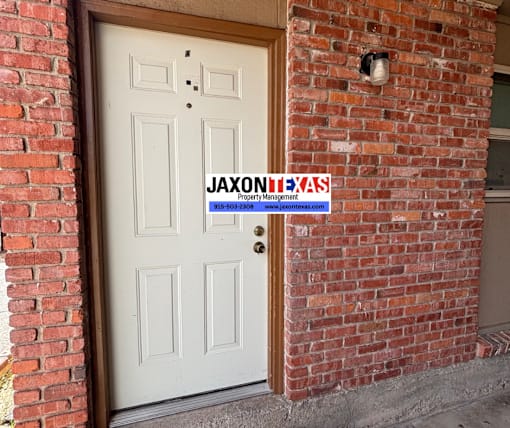 A white door with a sign that says "Jaxonixas Property Management" on a brick wall.