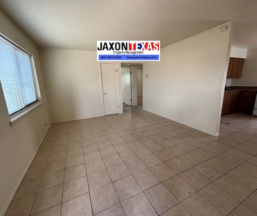 A room with a tiled floor and a JAXON PROPERTY MANAGEMENT sign on the wall.
