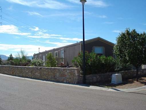A street view with a house, a lamp post and a stone wall.