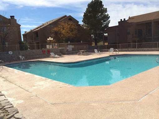 A swimming pool surrounded by a stone wall and a fence.