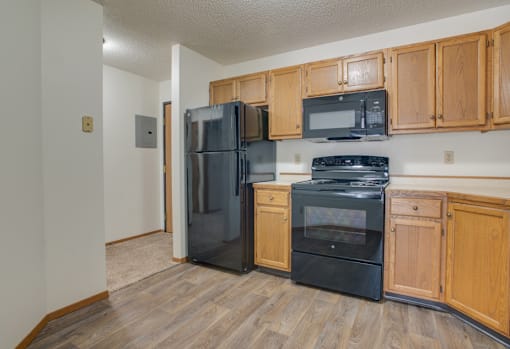 A kitchen with black appliances and wooden cabinets.