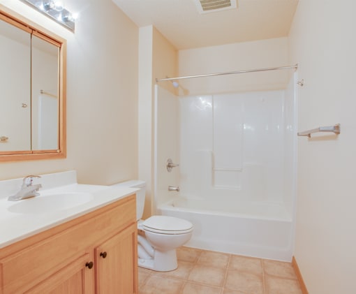 A white toilet sits next to a sink in a bathroom, Kassenborg Apartments, Moorhead, MN, 56560
