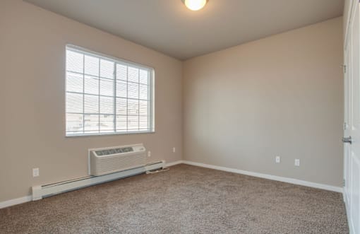 A room with a window and a wall-mounted air conditioner.