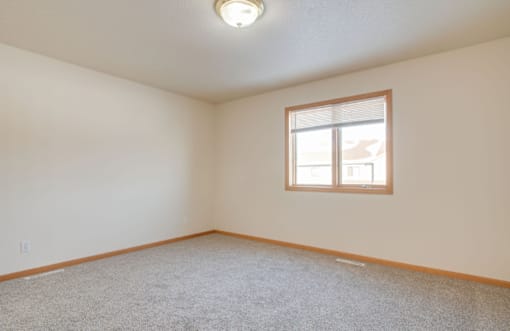 A room with a window and carpeted floor.