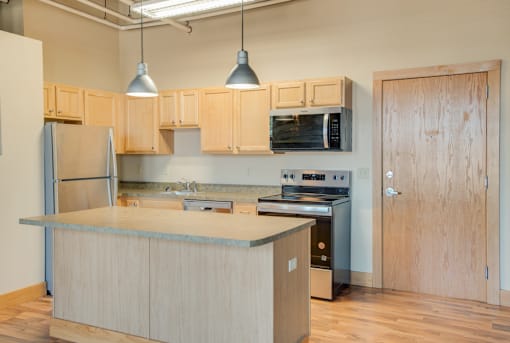 A kitchen with wooden cabinets and a stainless steel refrigerator, Kassenborg Apartments, Moorhead, MN