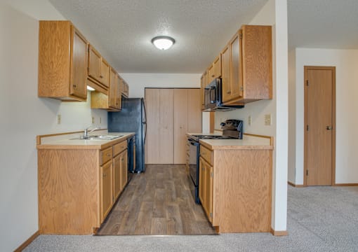 A kitchen with wooden cabinets and a black refrigerator.