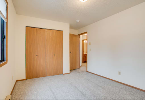 A room with a carpeted floor and two wooden doors.