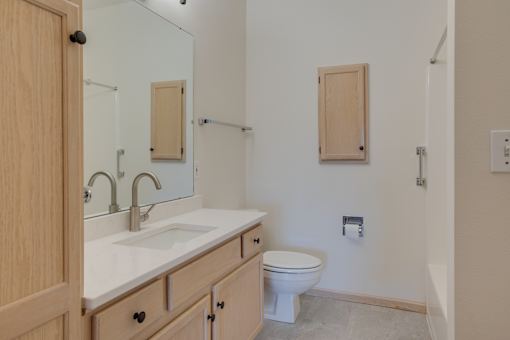 A bathroom with a sink, toilet and mirror. at Eighth Street Manor Apartments, Fargo, 58103
