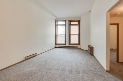 a bedroom with two windows and a carpeted floor