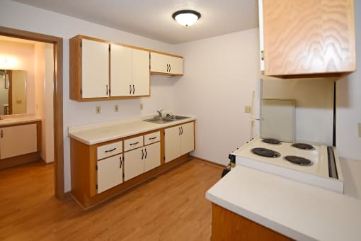 a kitchen with white cabinets and a stove and a sink at Aspen Apartments, Hudson