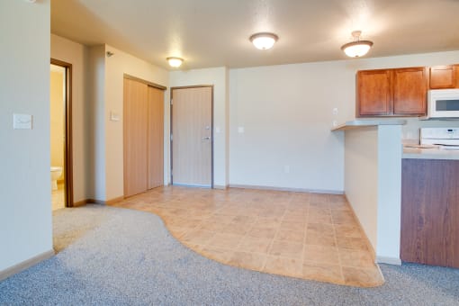 an empty living room and kitchen with a microwave and a sink at Waterstone  Apartments, Moorhead, MN