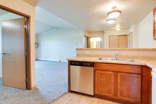 a kitchen with a sink and a dishwasher and a door to a living room at Waterstone Apartments, Minnesota