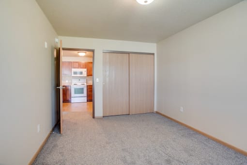 an empty living room with a door to a kitchen at Waterstone Apartments, Moorhead