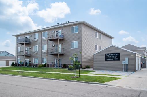 a large apartment building with balconies and a sign that reads condominium  at Courtyard Apartments, Moorhead, 56560