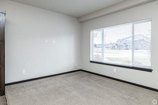 Empty room with a window overlooking a residential area.