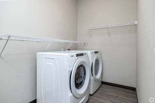Two white front load washing machines in a small laundry room.