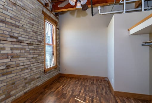 A room with a brick wall and wooden flooring, Kassenborg Apartments, Moorhead, Minnesota