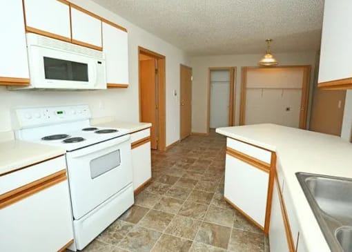 A kitchen with white appliances and brown cabinets.
