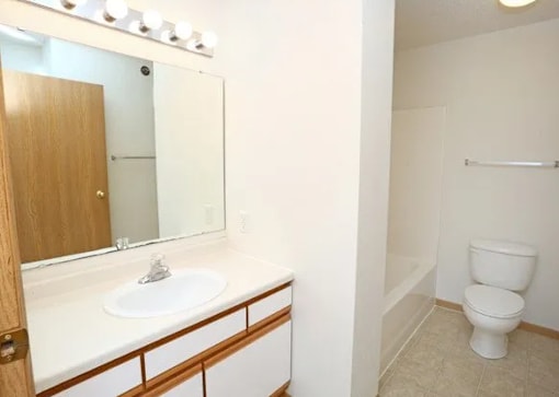 A white toilet sits in a bathroom next to a sink.