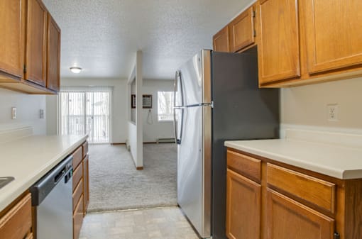 A kitchen with a black refrigerator and wooden cabinets.