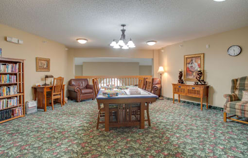 A room with a carpeted floor and a large table surrounded by chairs at Savanna Apartments, St Cloud, Minnesota