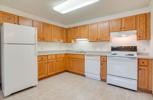 A kitchen with wooden cabinets and white appliances at Savanna Apartments, St Cloud