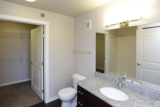A bathroom with a toilet, sink, and mirror.