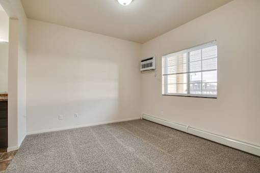 A room with a window and a carpeted floor.