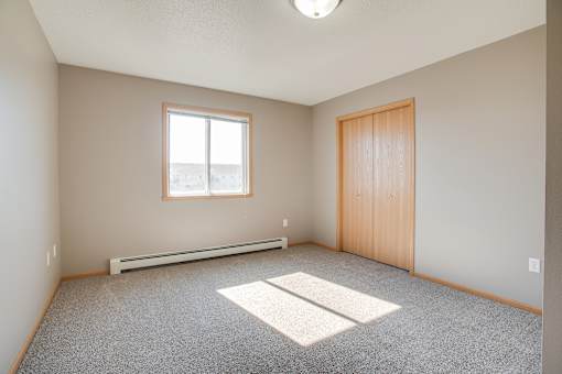 A room with a window, a door, and a carpeted floor.