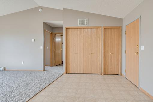 Three wooden doors are closed in a room with a carpeted floor.