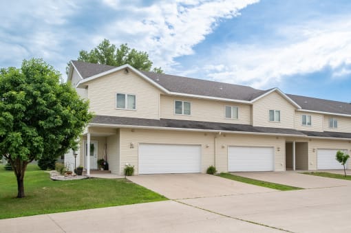 a house with two garages and a tree on the side of the road