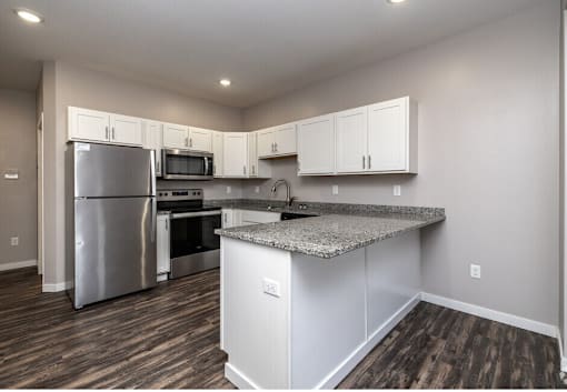 A kitchen with a granite countertop and stainless steel appliances.