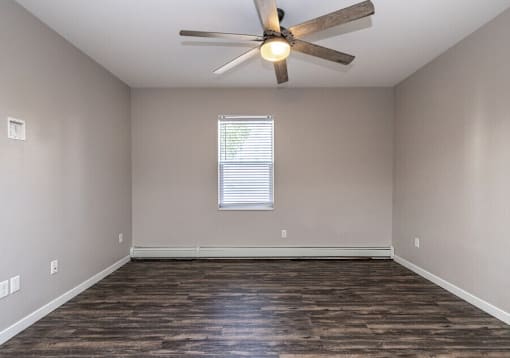 A room with a ceiling fan and wooden flooring.