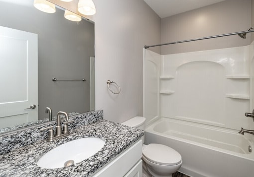 A bathroom with a granite countertop and white fixtures.