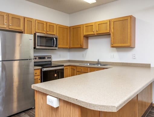 A kitchen with wooden cabinets and a stainless steel refrigerator.