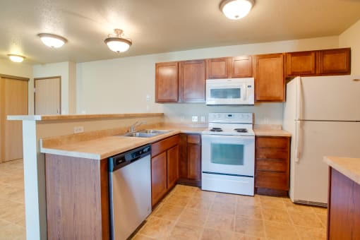 a kitchen with white appliances and wooden cabinets at Waterstone Apartments, Moorhead, 56560
