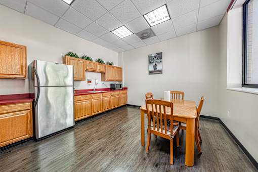 A community room kitchen with a table and chairs.