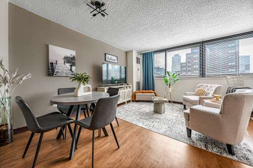 A beautiful and spacious living room with a dining table and chairs and a large window with a lot of sun light in apartment in Jersey City NJ