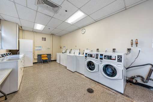 a laundry room with washers and dryers and a row of washing machines