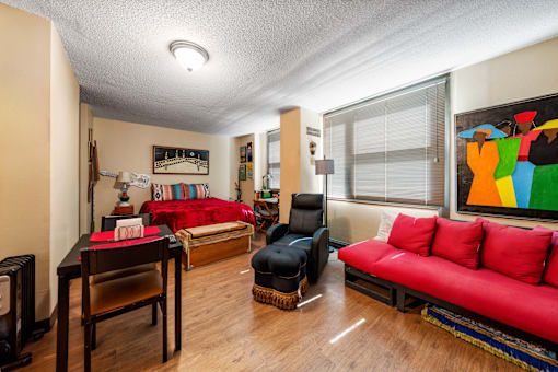 A living room with a red couch and a black chair.