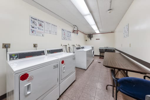 a laundry room with washes and dryers and a table