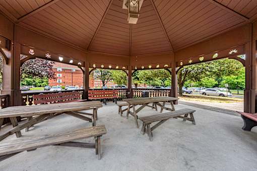 a covered pavilion with picnic tables in a park