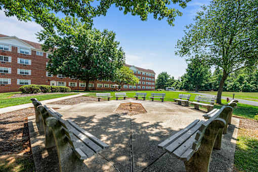 a park with benches and trees in front of a building