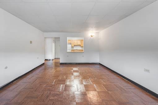 a living room with white walls and a wooden floor and a window