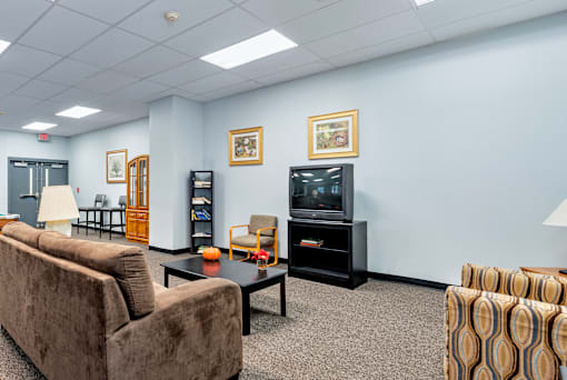 A living room with a brown couch, a coffee table, and a television.