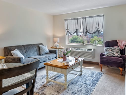 A living room with a grey couch, a wooden coffee table, and a purple armchair.