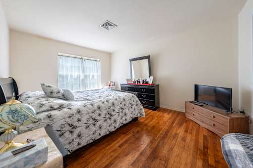 a bedroom with a bed and a dresser and a tv